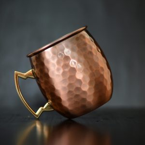 Close-up of a luxurious copper mug with a hammered finish and metallic handle.