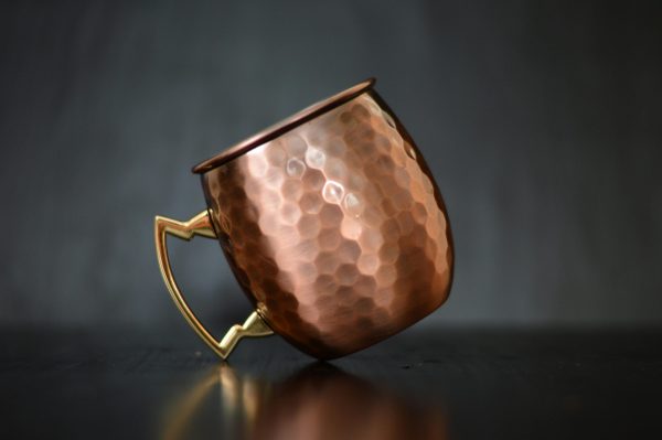 Close-up of a luxurious copper mug with a hammered finish and metallic handle.